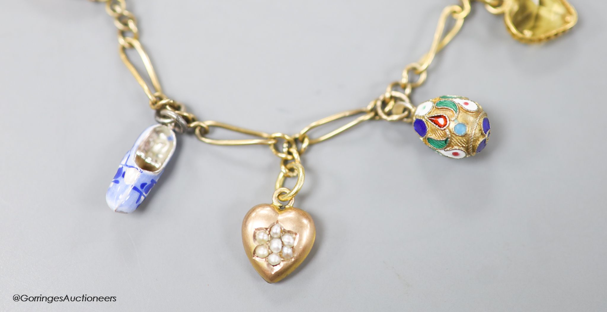 A small Edwardian 9ct gold charm bracelet, hung with eight assorted charms, approx. 16cm, gross weight 9.7 grams.